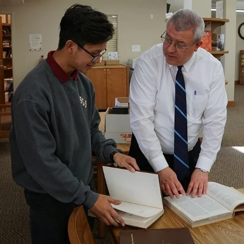 student and teacher looking at textbooks